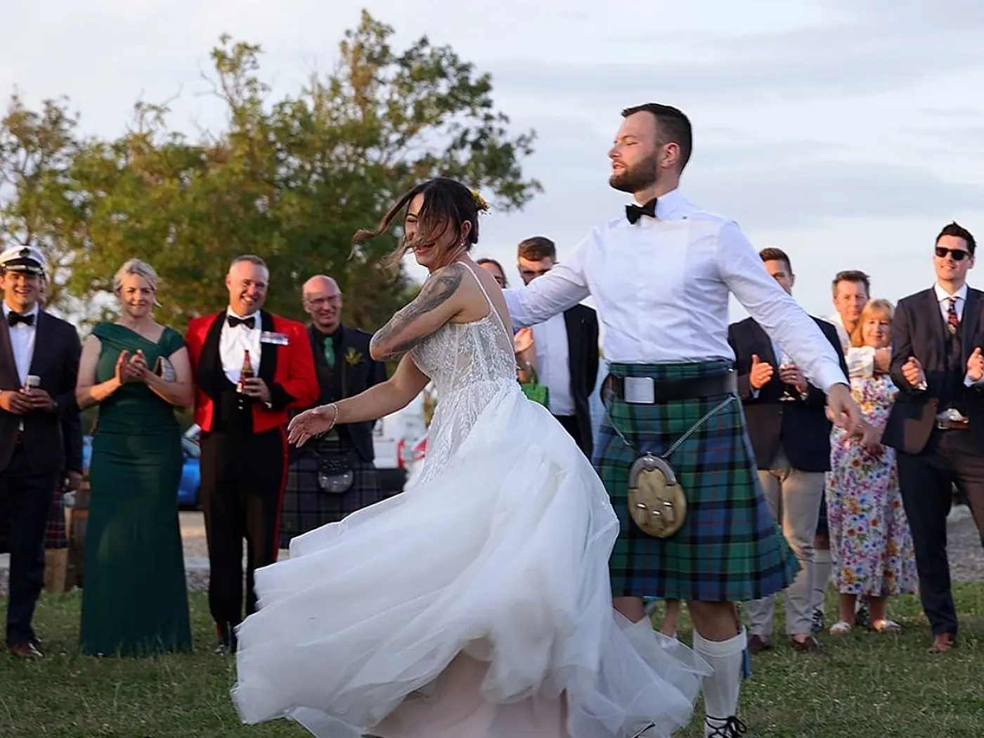 A bride mid-spin in her ceilidh first dance while guests clap her on